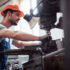Experienced operator in a hard hat. Metalworking industry concept professional engineer metalworker operating CNC milling machine center in manufacturing workshop.